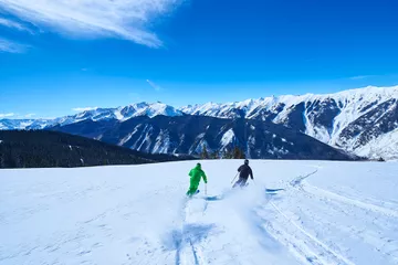 Two people skiing down snow covered ski slope, Aspen, Colorado